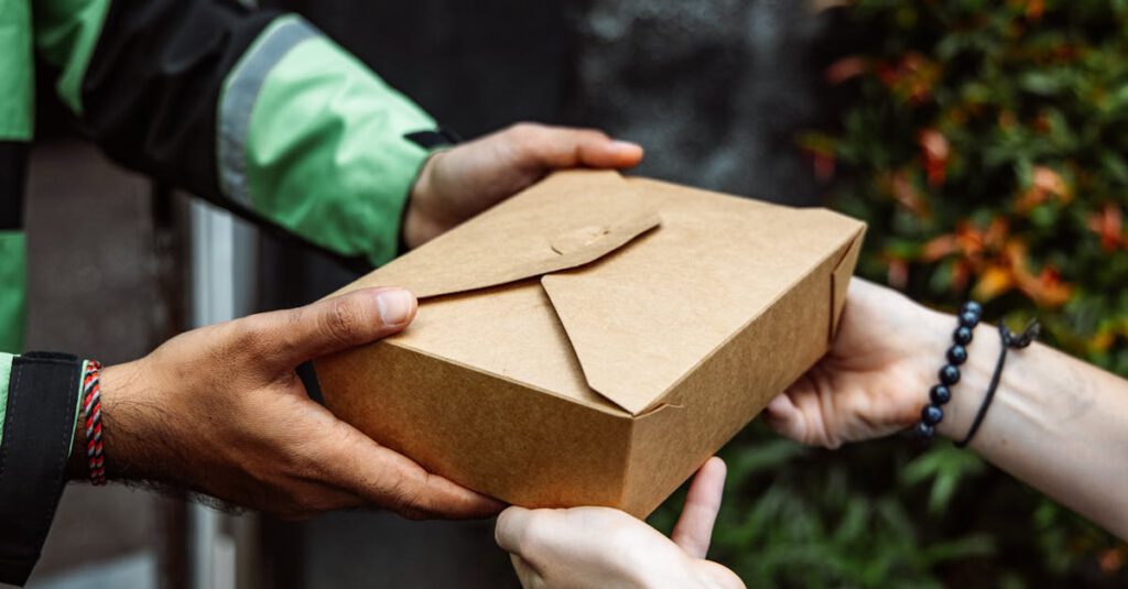 Close-up of a delivery person handing over a box to a customer outdoors.
